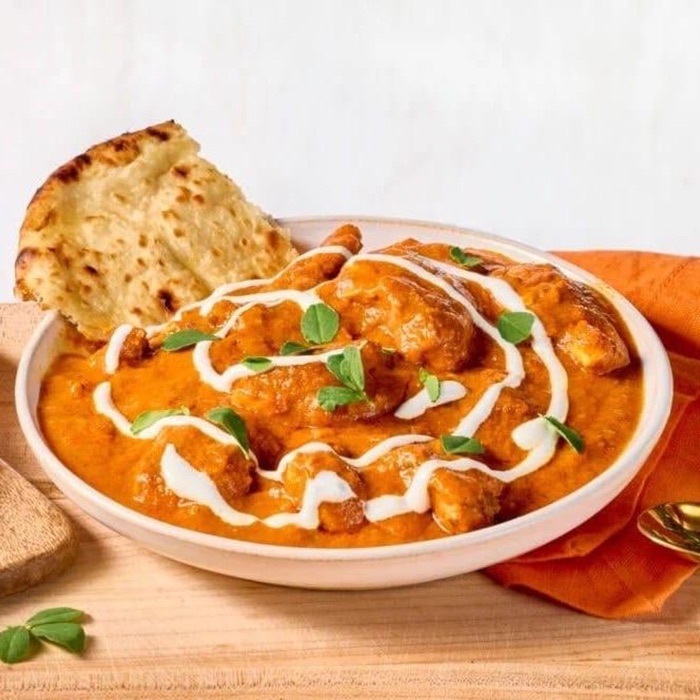 Butter chicken swirled with cream next to naan