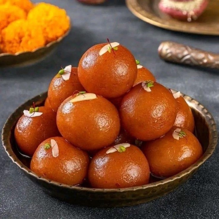 Gulab jamun stacked in a brass bowl